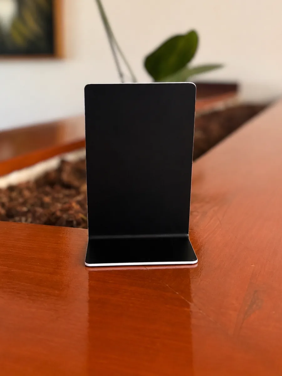 El reverso de la placa, negro liso y sin impresión, apoyado en su base.